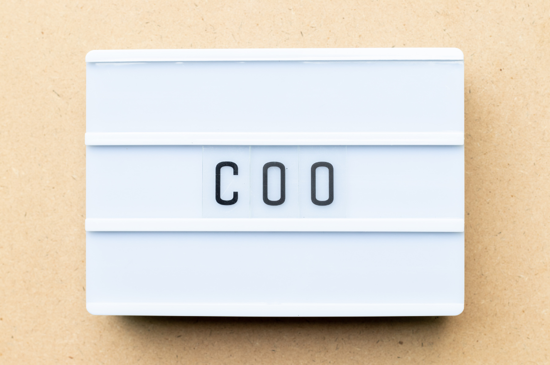 Lightbox showing "COO" on a desk, symbolizing the role of a Chief Operating Officer in business leadership.