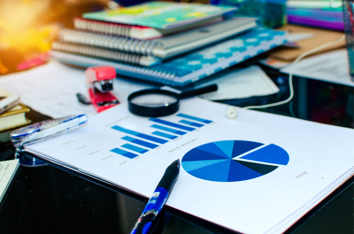 Sales report with bar and pie charts on a cluttered desk, representing operational analysis and strategy.