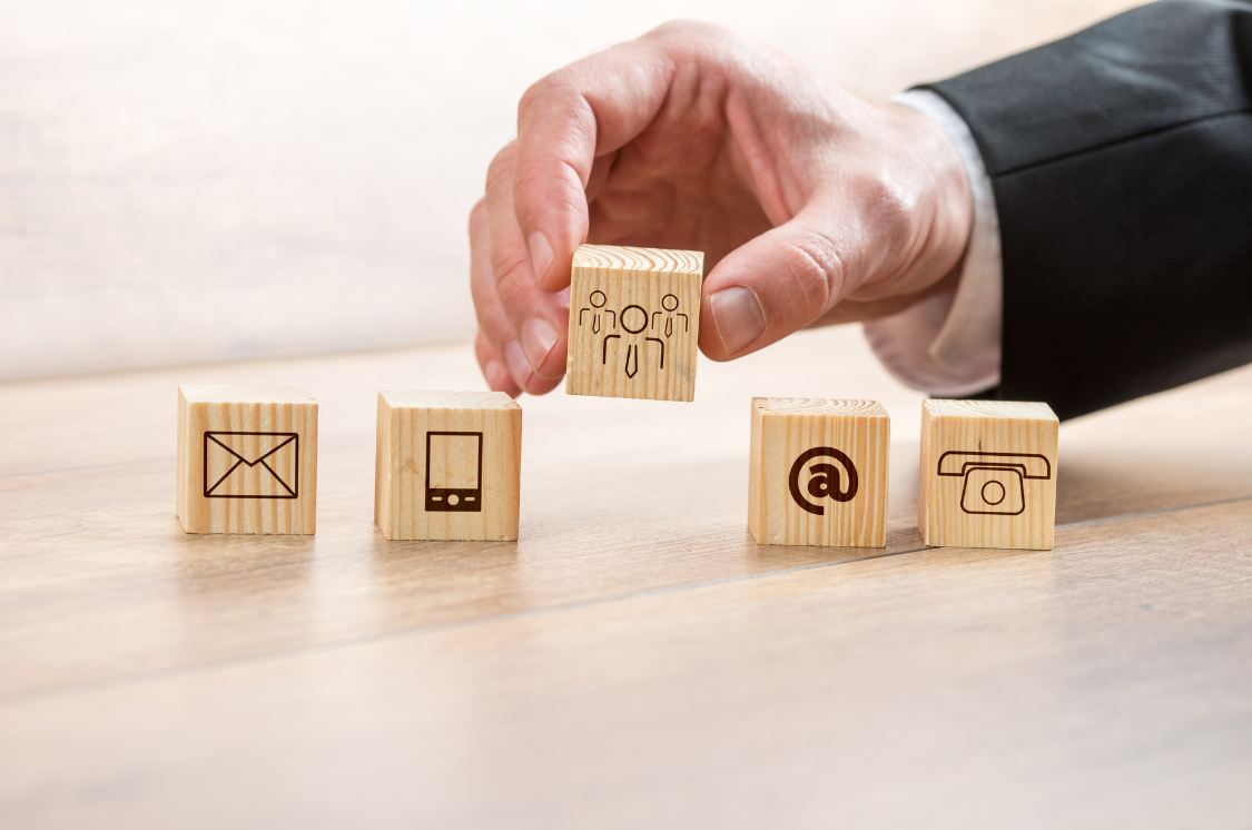 Hand placing a wooden block with business icons, representing strategic operations consulting.