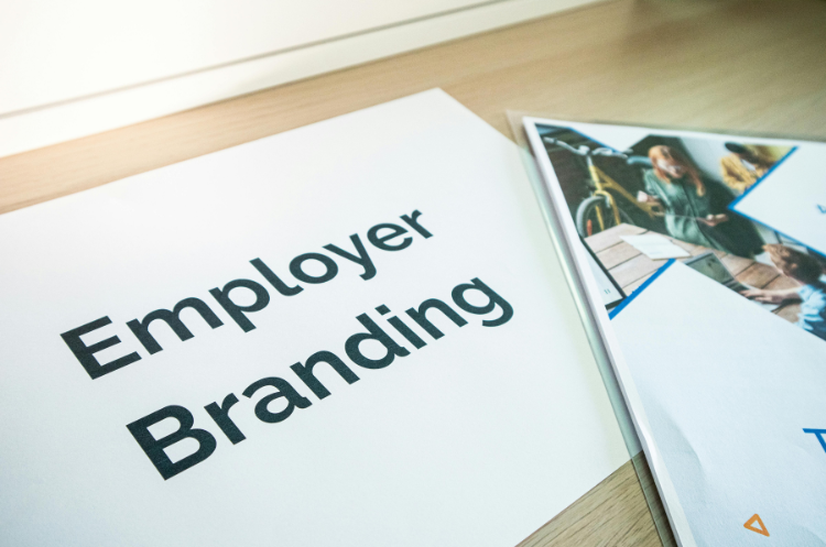 A document with the words "Employer Branding" in bold text resting on a desk next to a company brochure, illustrating key materials for attracting top talent.