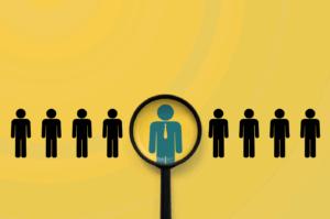 Magnifying glass highlighting a standout professional figure among a row of people icons, symbolizing HR leadership, talent selection, and CHRO role.