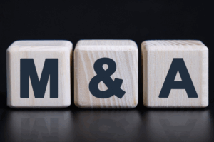 Wooden blocks displaying the letters M & A, representing mergers and acquisitions in business and corporate finance.