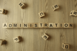 Wooden letter blocks spelling 'ADMINISTRATION' on wooden surface, symbolizing strategic role and importance of administrative managers in modern organizations