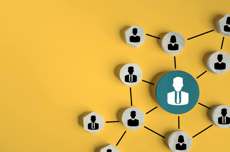 A wooden figure in a tie stands out from a line of peers, symbolizing a professional expert who accelerates leadership growth within an organisation.