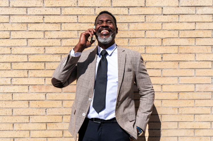 Professional senior executive making a phone call against a brick wall background.