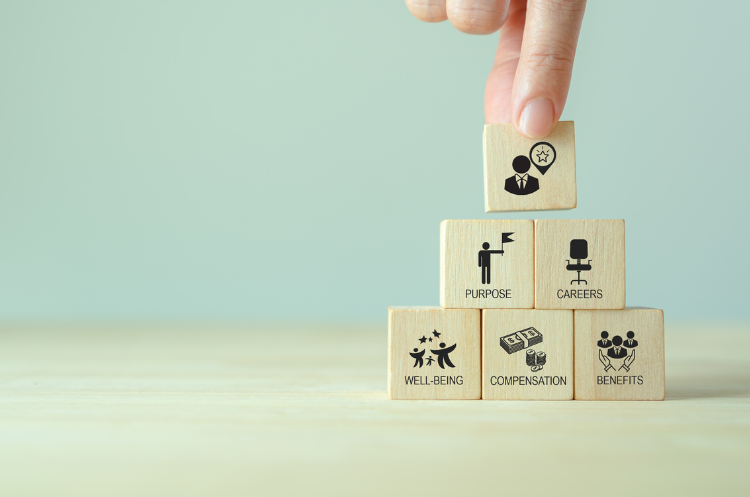 Visual representation of building an employee retention strategy using wooden blocks to form a pyramid of core values.