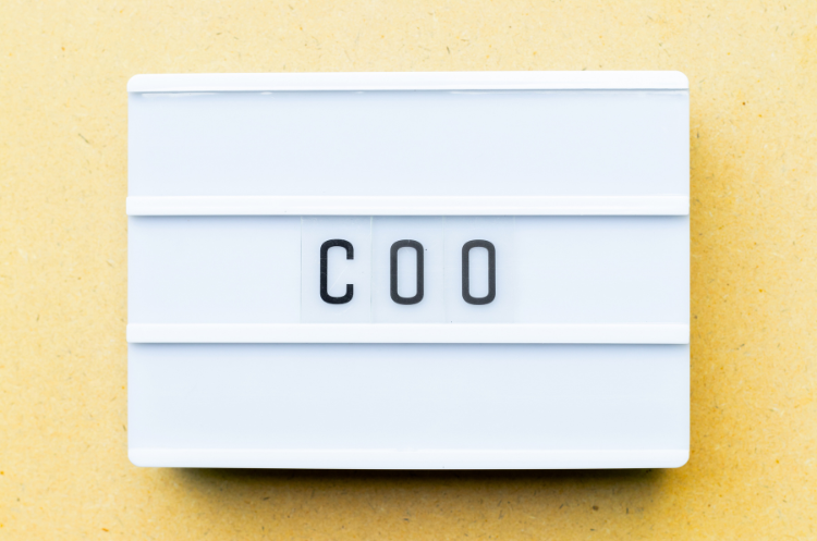 White cinematic lightbox displaying the acronym COO for Chief Operating Officer on a tan background