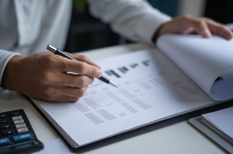 A Director of Regulatory Affairs reviewing complex compliance data, charts, and financial documents on a clipboard to develop a global market entry strategy.