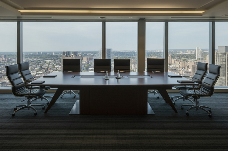 An empty, modern executive boardroom in a high-rise building with a panoramic view of the Singapore skyline. The setting symbolizes the Board of Directors roles and corporate governance responsibilities for senior leaders in Singapore.