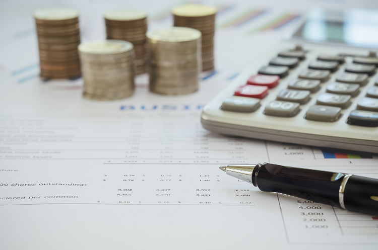 Close-up of financial documents with stacked coins, a calculator, and a pen, representing budgeting, accounting, financial planning, or corporate treasury management.