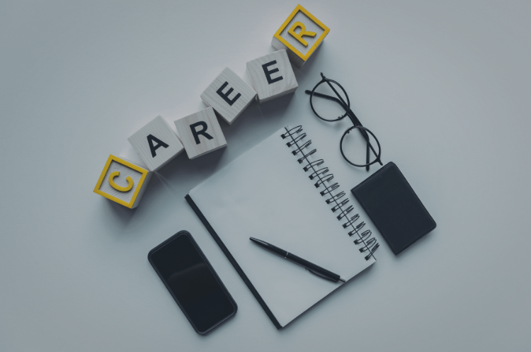 Career planning workspace featuring the word "CAREER" spelled with letter blocks, alongside a notebook, pen, glasses, smartphone, and wallet, symbolizing career transition and professional growth in Singapore.