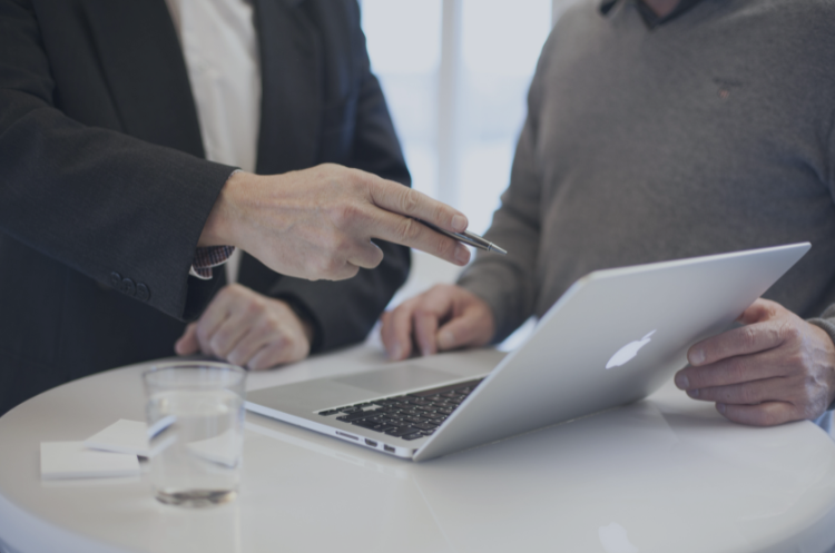 Two business professionals discussing strategy over a laptop, representing independent consulting, client collaboration, and professional advisory services.