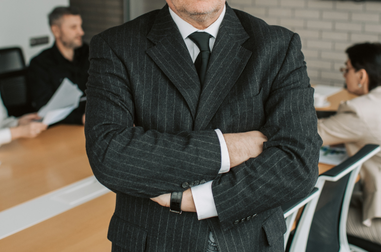 Experienced business executive standing confidently in a modern office with colleagues in the background, representing career change opportunities, leadership, and second careers after 50.