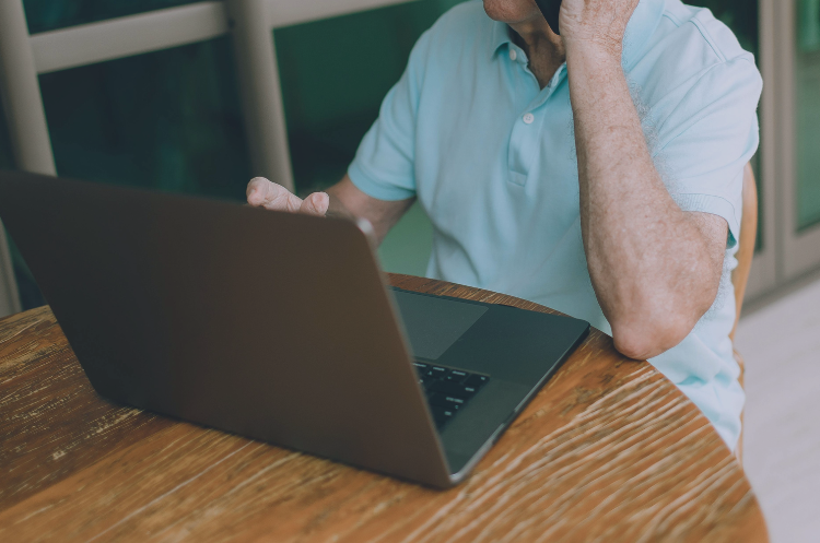Experienced professional working on a laptop while talking on the phone from home, representing flexible work arrangements, remote work, and consulting opportunities.