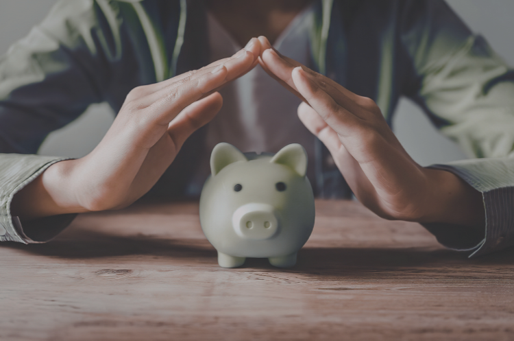 Person protecting a piggy bank with their hands, symbolizing asset management and financial security in Singapore.