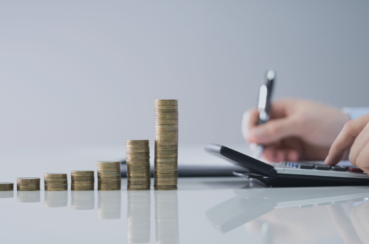 Finance professional calculating figures beside stacks of coins representing financial growth.