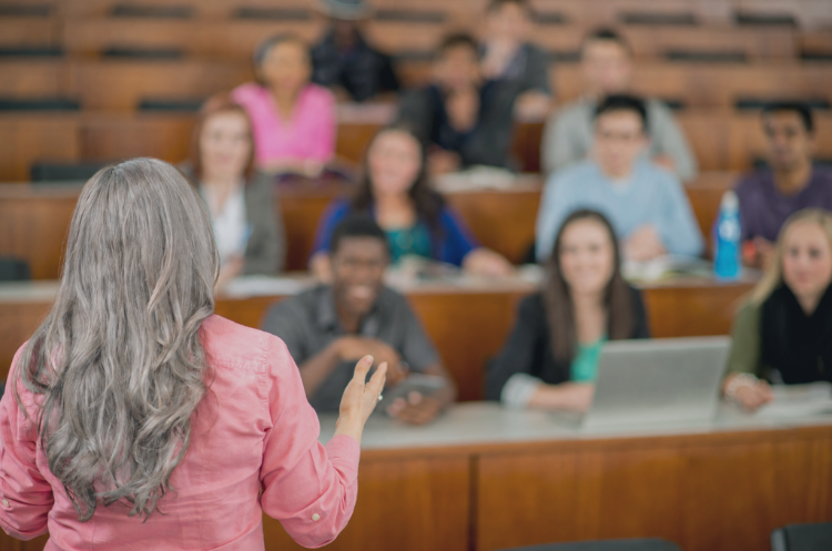 Experienced female professor delivering a lecture to university students in a classroom.