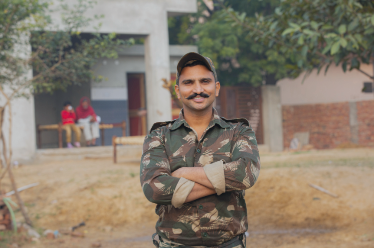 Indian man in camouflage military uniform standing outdoors with arms crossed, representing second career opportunities for ex-servicemen and retired defence officers.